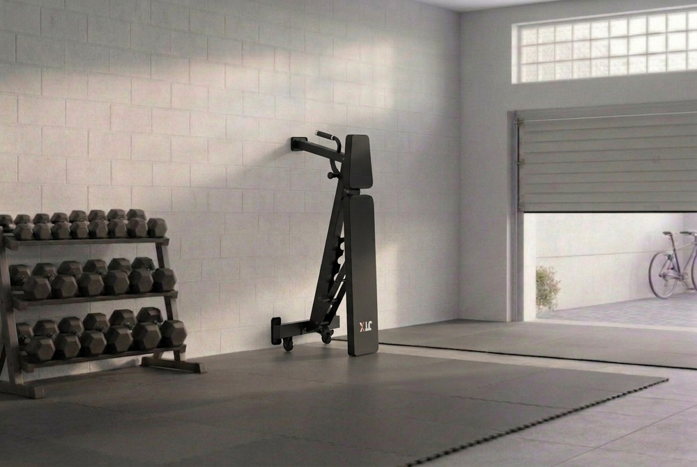 JTX FID Bench stored upright against a wall in a garage home gym