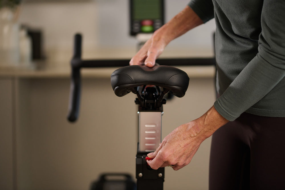 Person adjusting the seating position on a JTX Ignite AirX Rider bike.