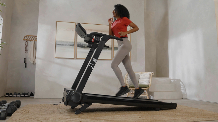 Woman running at an incline on a JTX treadmill in their living room.