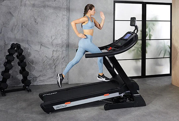 Woman running at an incline on a JTX Club Pro treadmill in a home gym.