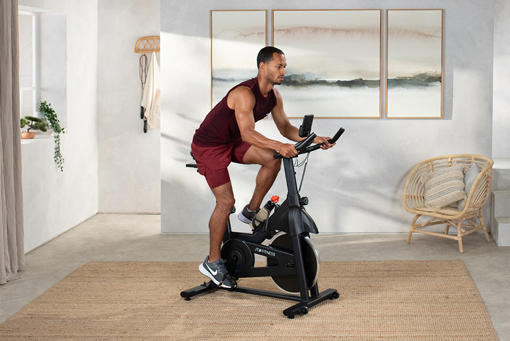 Man riding a JTX Cyclo-3M exercise bike in their living room.