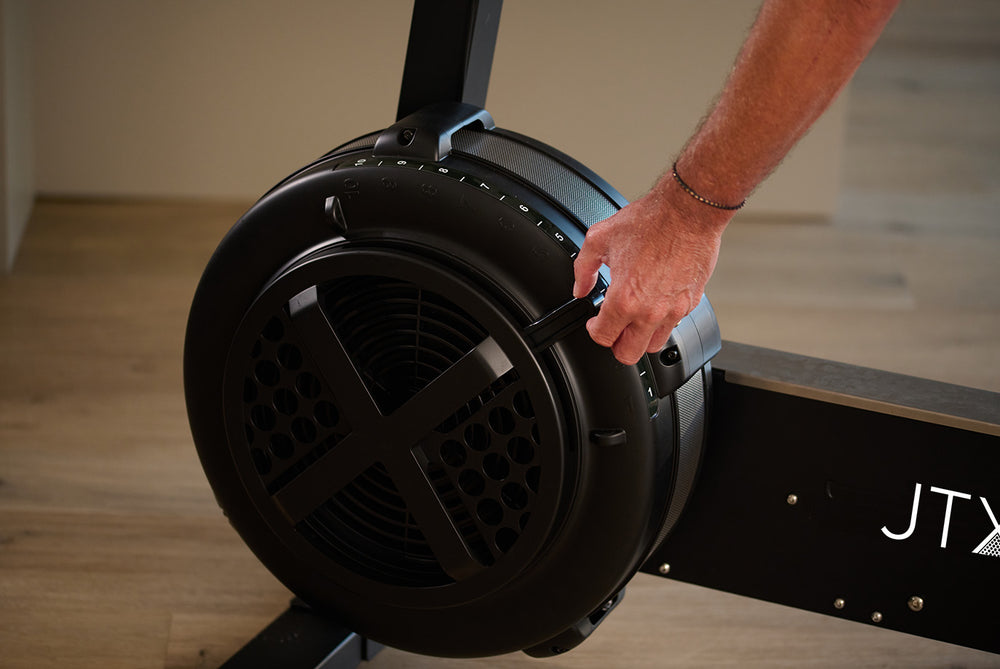 Person manually adjusting the resistance setting on the fan wheel of the Ignite AirX Rider bike.