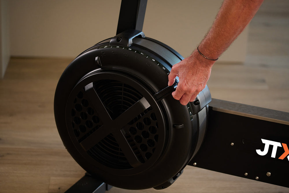 Person manually adjusting the resistance setting on the fan wheel of the Ignite AirX Rider bike.