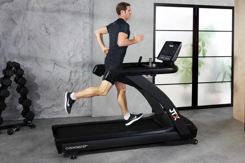 Man running on a JTX Club Pro treadmill in a home gym.