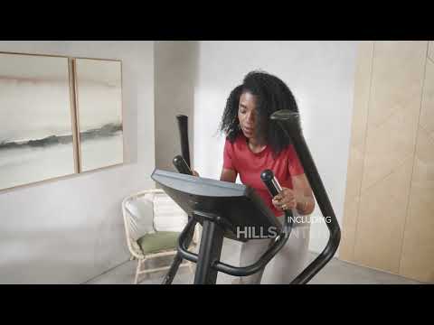 Woman using the hand pulse sensors on the static handles of a JTX Zenith Rise cross trainer in their living room.