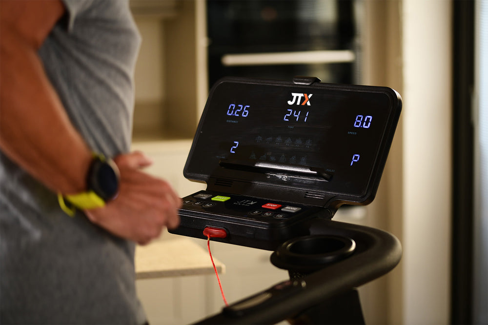 Close-up of a treadmill control panel with digital display and buttons, blurred background.