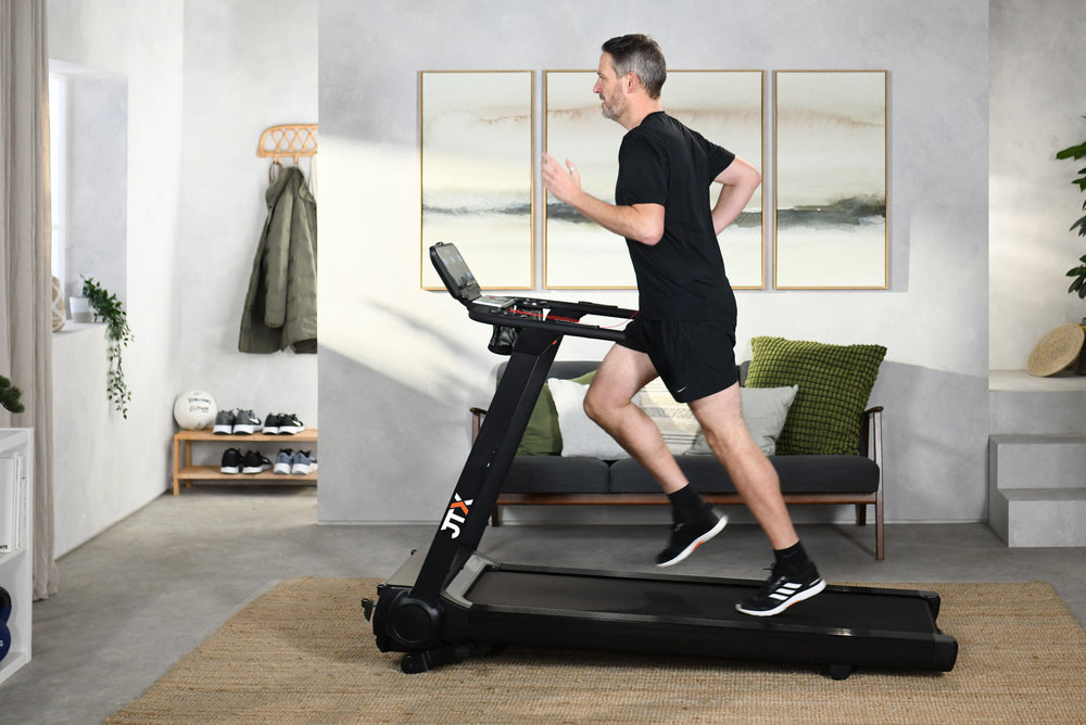 Man running at an incline on a JTX RunRise XL treadmill in their living room.