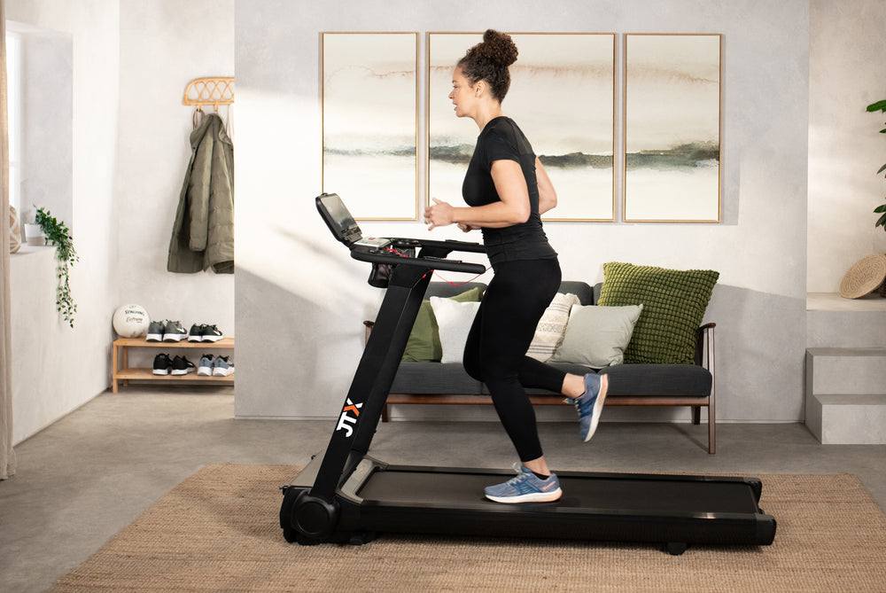 Woman running on a JTX RunRise XL treadmill in their living room.