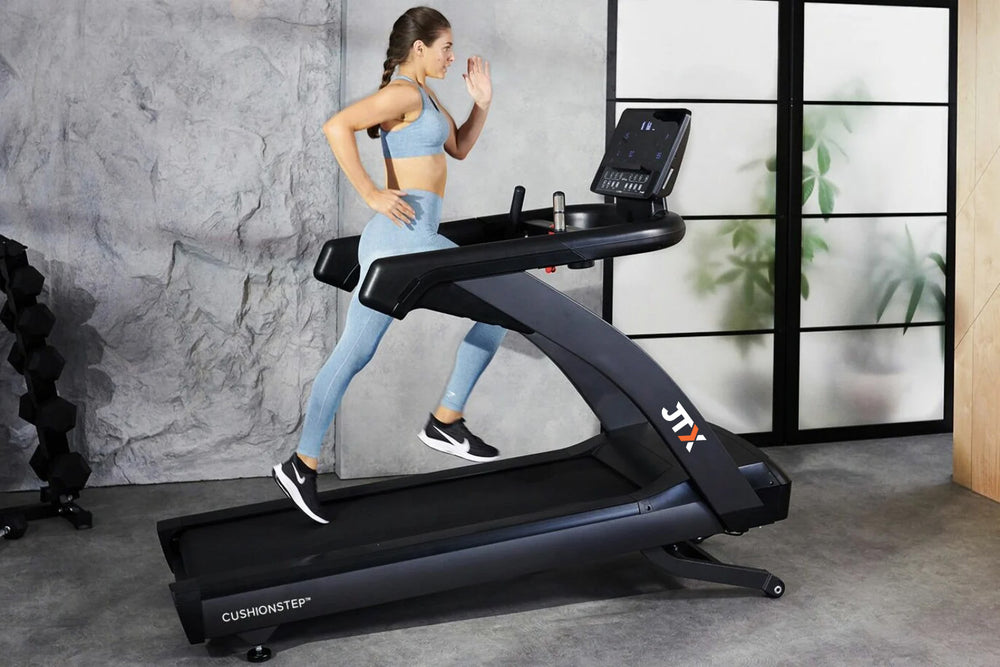Woman running at an incline on a JTX Club Pro treadmill in a home gym.