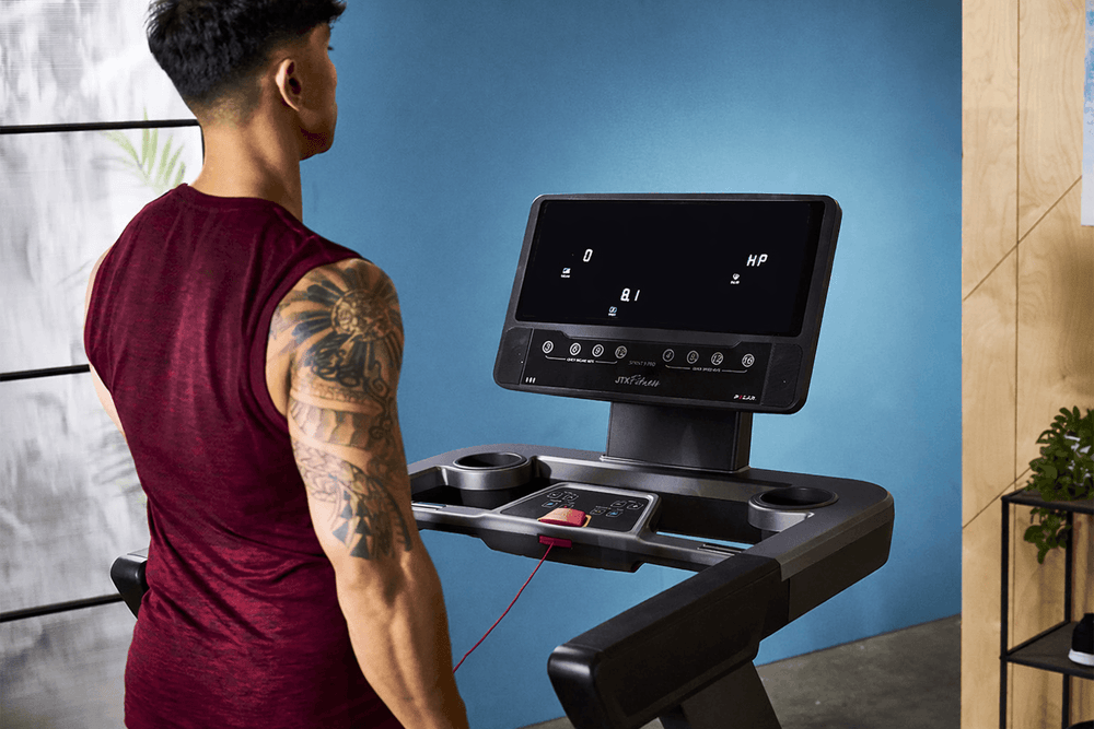 Computer console of a JTX Sprint-9 Pro treadmill while a man is stood on the machine.