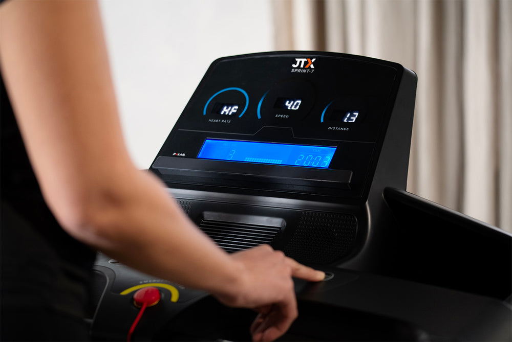 Person using a JTX Sprint-7 treadmill with a digital display showing settings and metrics.