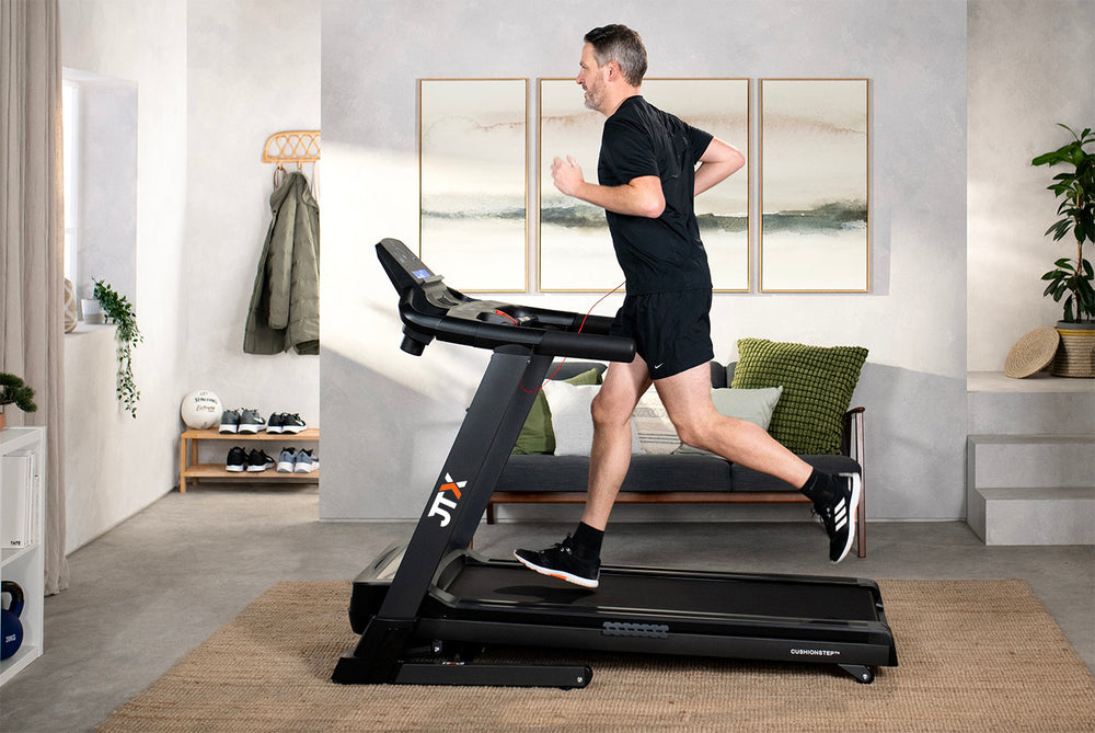 Man running on a JTX Sprint-7 treadmill in a modern living room.