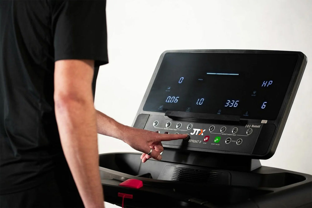 Person interacting with the digital console of the JTX Sprint-8 treadmill.
