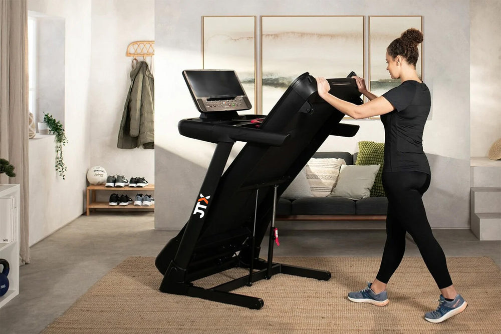 Woman folding up the deck of a JTX Sprint-8 treadmill.