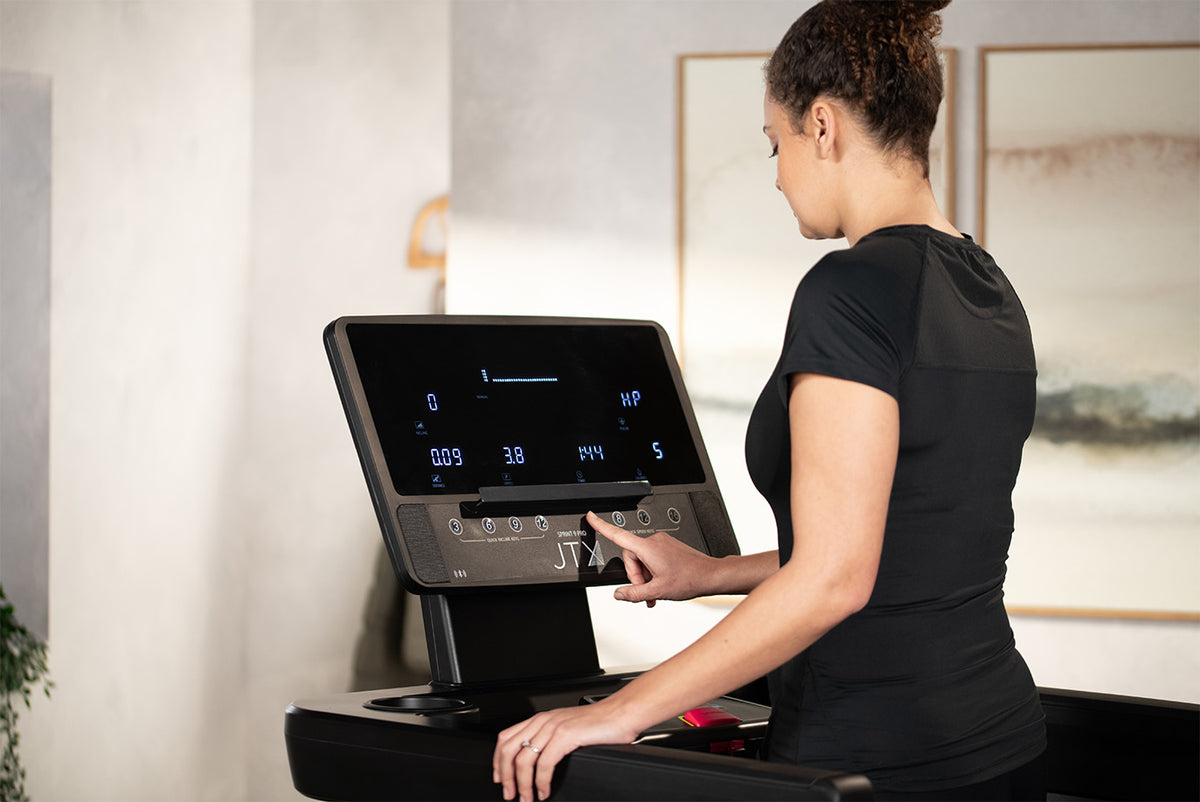 Woman interacting with the console of a Sprint-9 Pro treadmill.