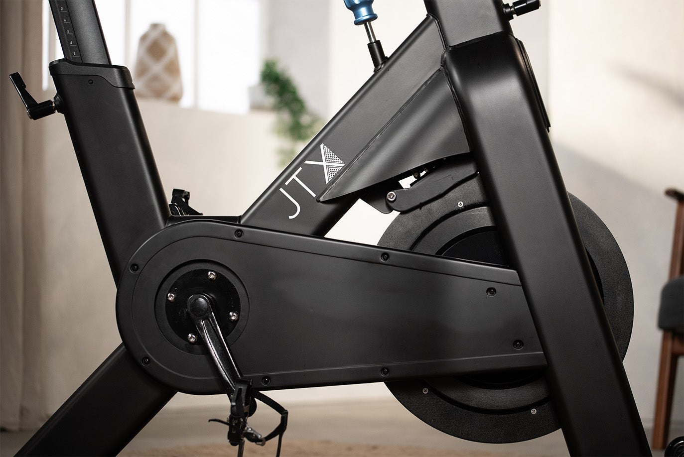 Side shot of JTX studio bike showing crank, pedals and flywheel.